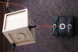 A light wooden box held by red tethers, seen from beside the upper Gametrak.