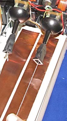 Two copper-coloured fingerboard strips side by side in a white frame, each with a thin thread running along it from a black Gametrak joystick knob at the top.
